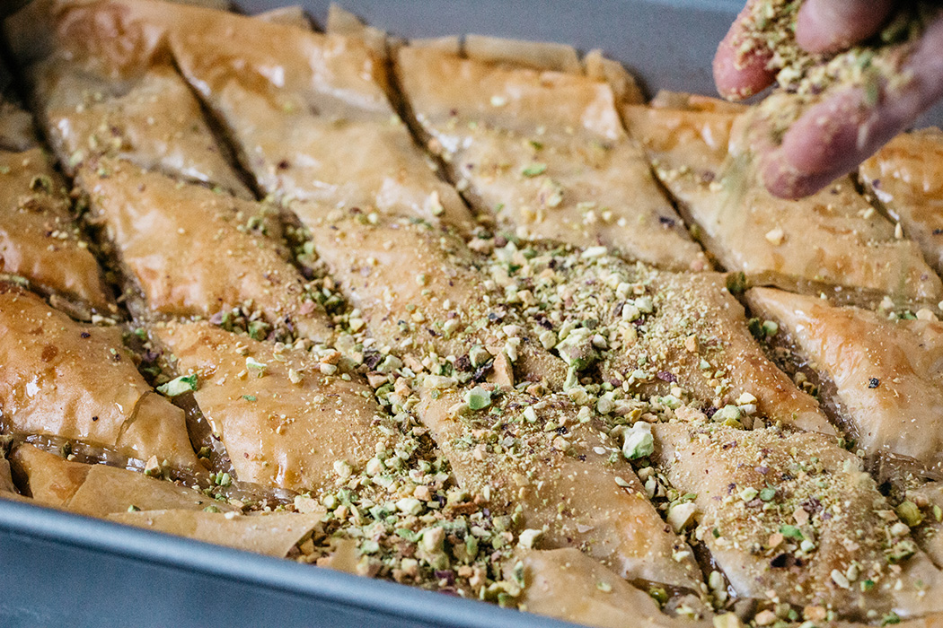 Asperjando pistachos sobre Baklava turco horneado justo antes de servir
