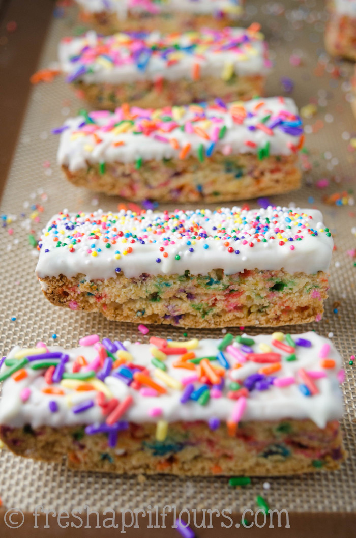 Biscotti Funfetti: Bizcochos crujientes rellenos de chispitas y bañados en chocolate blanco, perfectos para mojar en el café. Una fiesta en tu boca y tu taza!