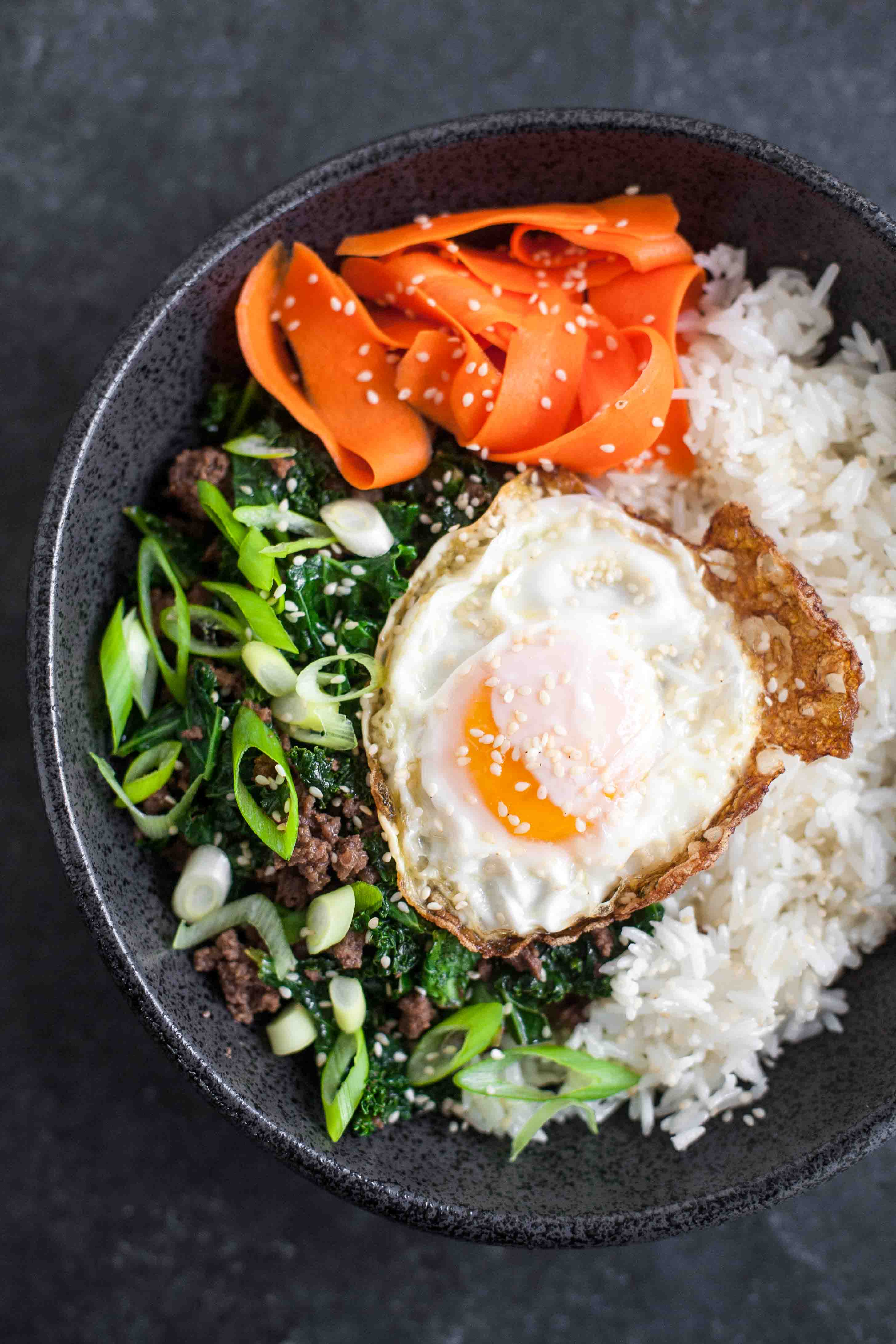 Cuencos de arroz de col y sésamo con huevos fritos y zanahorias en escabeche