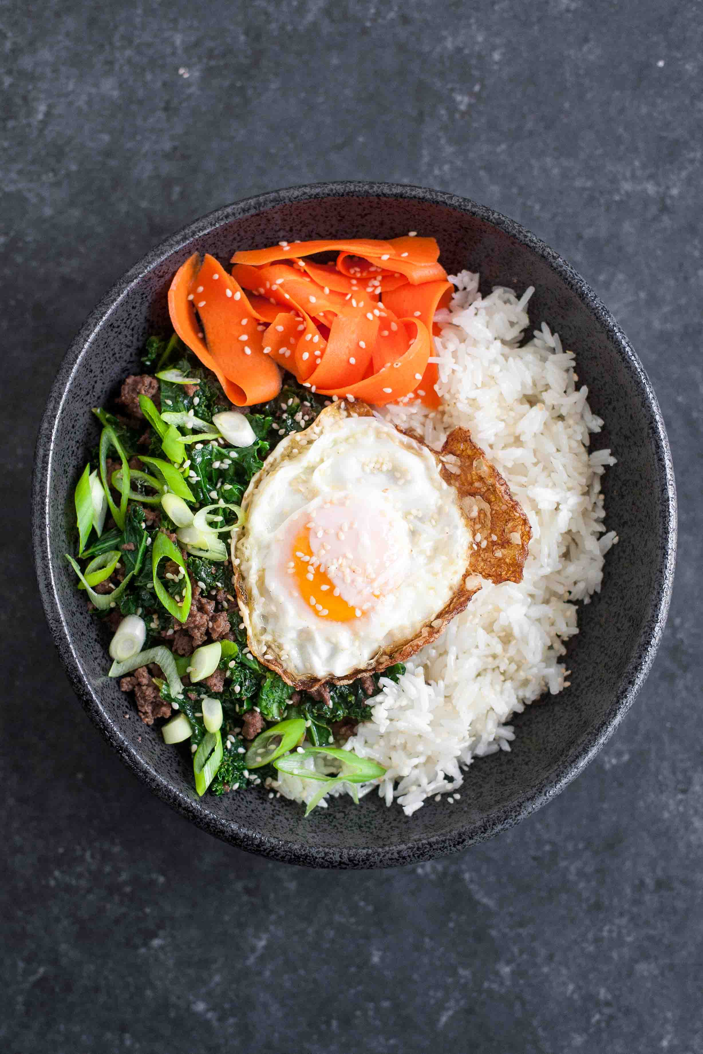 Cuencos de arroz de col y sésamo con huevos fritos y zanahorias en escabeche