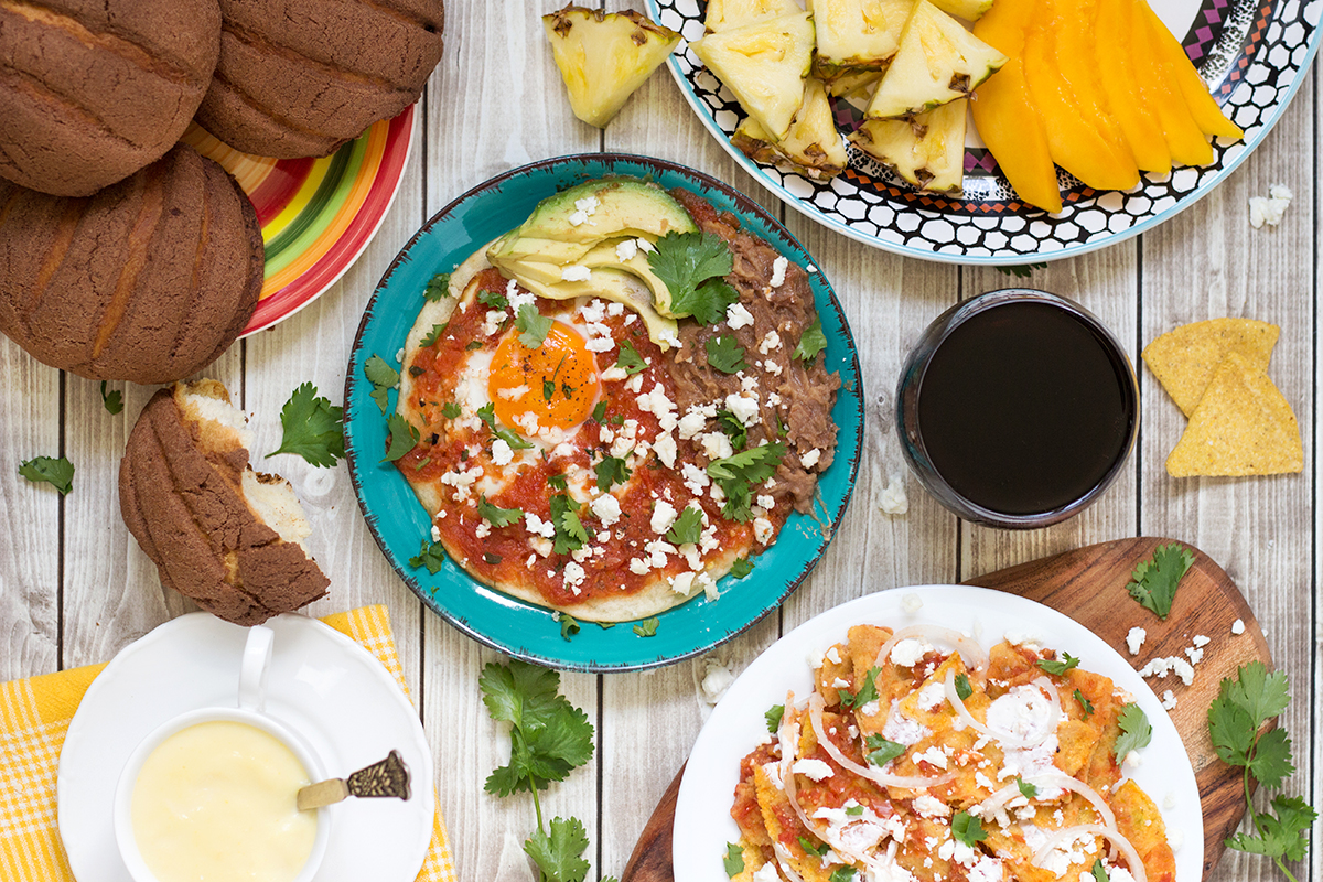 ¡Un vistazo al tradicional desayuno mexicano que incluye huevos fritos picantes (Huevos Rancheros), chips de tortilla en salsa (Chilaquiles), pan dulce y la bebida caliente de maíz (Atole)!