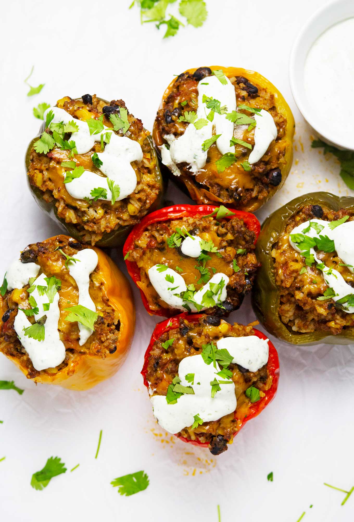 Estos pimientos rellenos de tex-mex de cocción lenta le dan un pequeño giro a la receta original de pimientos rellenos. ¡Se hacen en la olla de cocción lenta y se cubren con una increíble crema agria de cilantro para completar esta deliciosa y fácil comida!