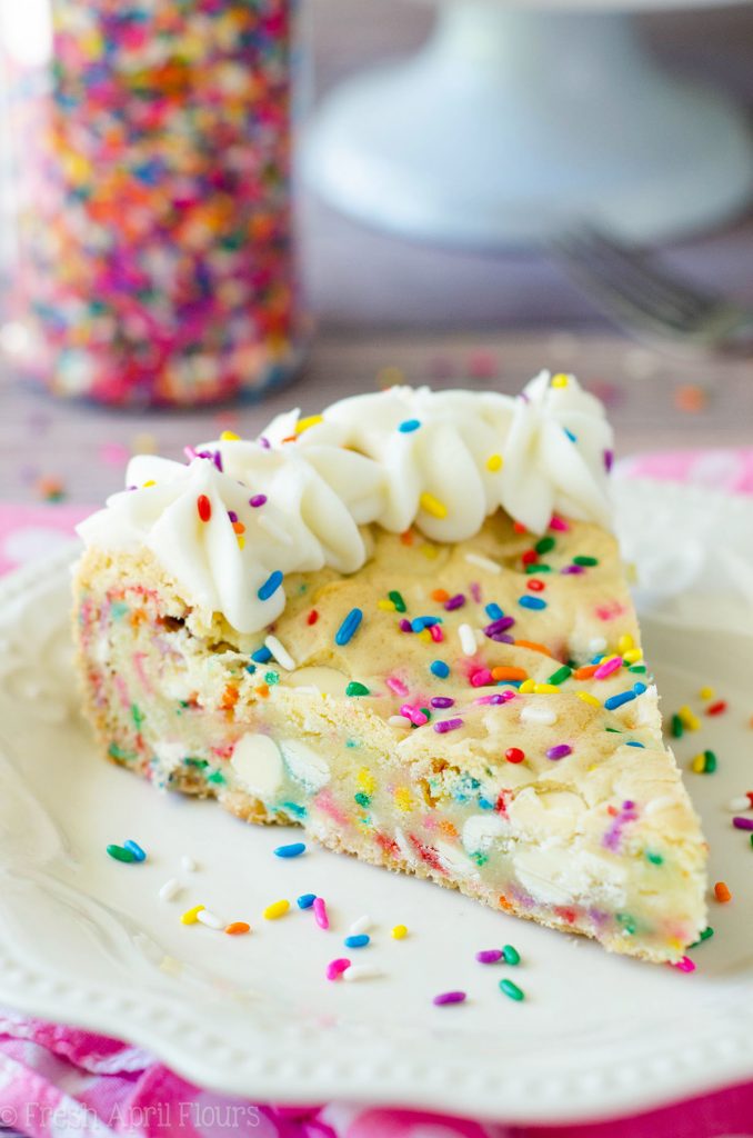 Funfetti Sugar Cookie Cake: Suave y mantecosa en el centro, crujiente alrededor de los bordes y llena de un montón de trocitos de chocolate blanco y chispas para celebrar cualquier ocasión. Rematado con una crema de mantequilla de vainilla de almendra cremosa y mantecosa.