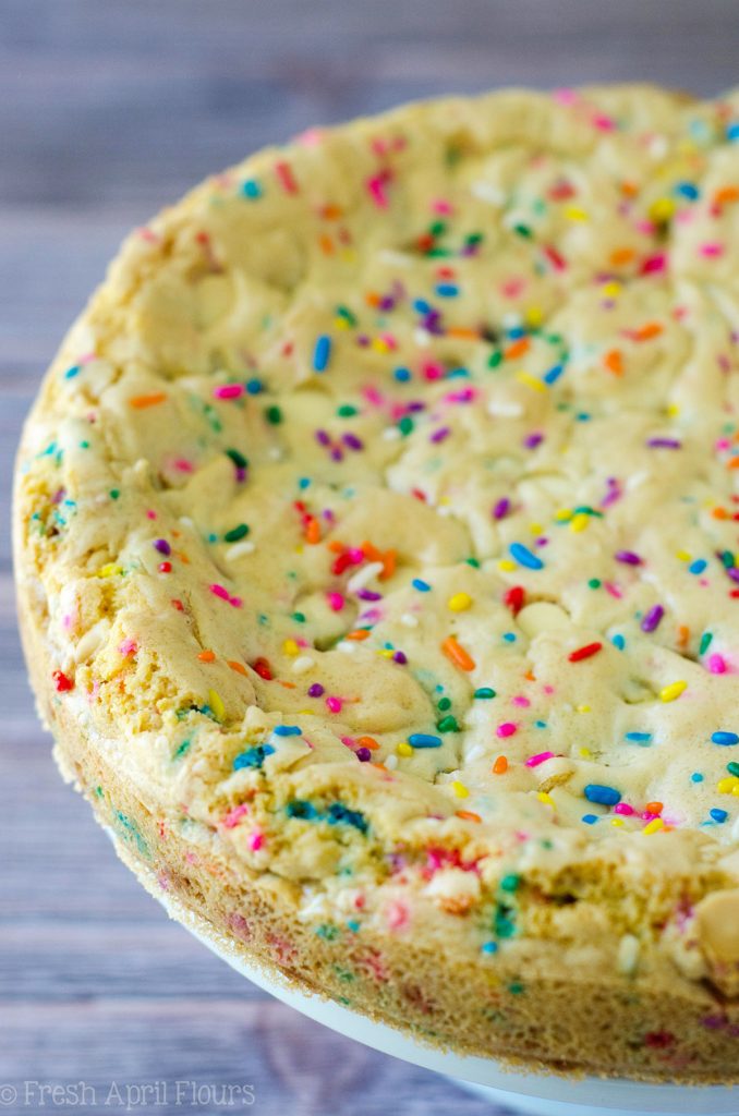 Funfetti Sugar Cookie Cake: Suave y mantecosa en el centro, crujiente alrededor de los bordes y llena de un montón de trocitos de chocolate blanco y chispas para celebrar cualquier ocasión. Rematado con una crema de mantequilla de vainilla de almendra cremosa y mantecosa.