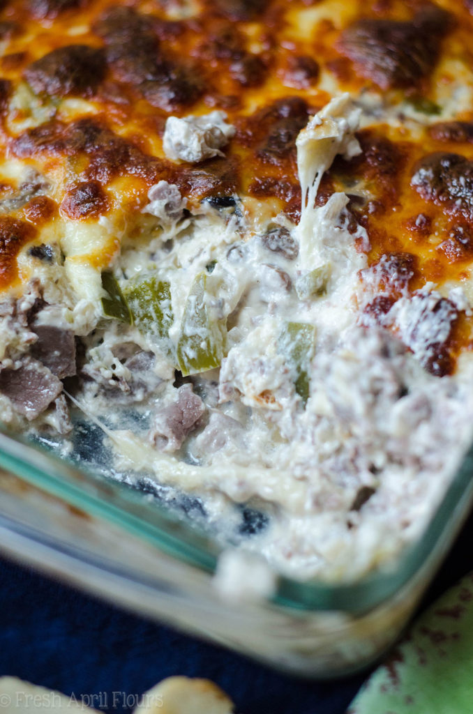 Philly Cheesesteak Dip: salsa cremosa rellena con sabrosas cebollas, pimiento verde, champiñones y carne asada, cubierta con una capa crujiente de queso provolone.