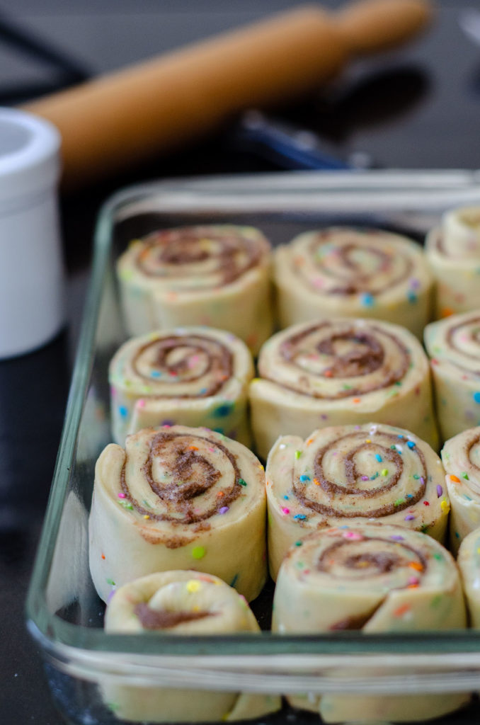 Rollos de canela Funfetti: rollos de levadura simples rellenos con canela dulce y pegajosa y salpicados con chispas. ¡Difunde con un glaseado de queso crema fácil para un desayuno o un placer indulgente!