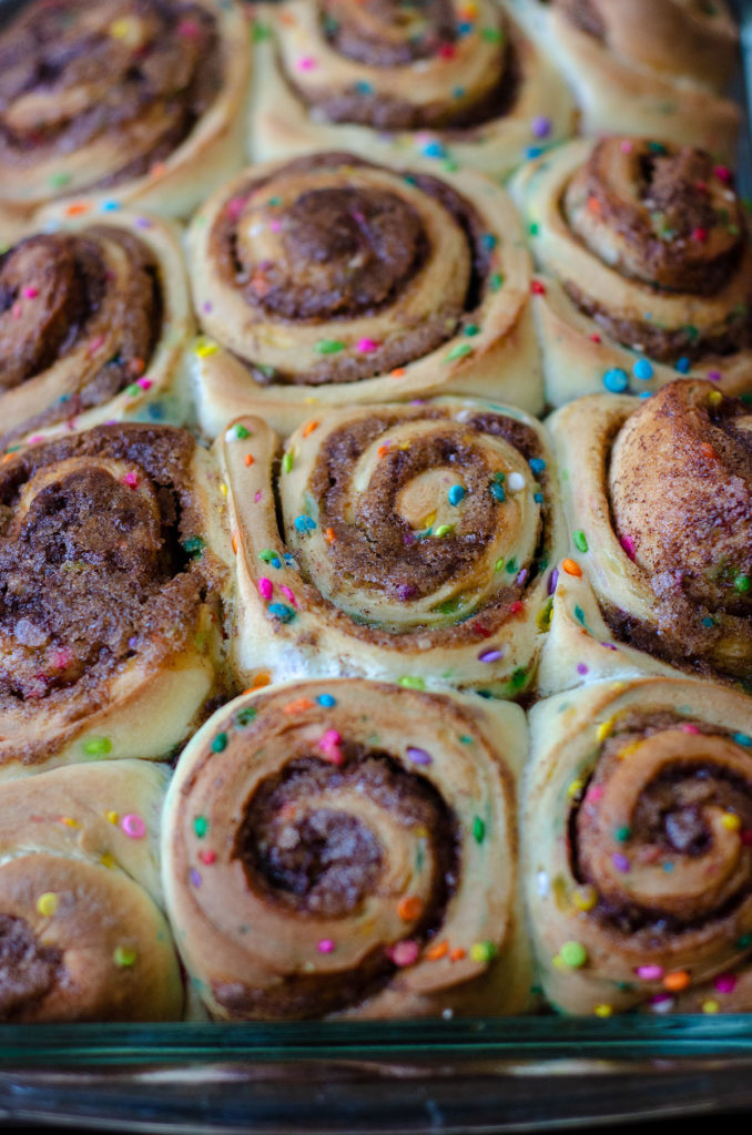 Rollos de canela Funfetti: rollos de levadura simples rellenos con canela dulce y pegajosa y salpicados con chispas. ¡Difunde con un glaseado de queso crema fácil para un desayuno o un placer indulgente!