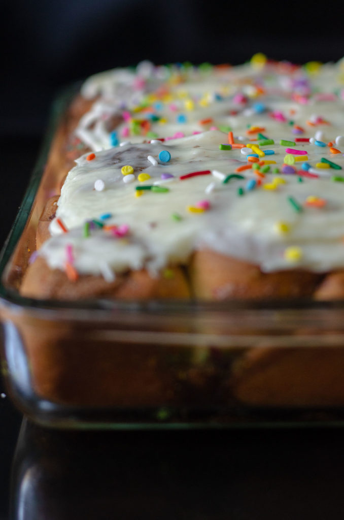 Rollos de canela Funfetti: rollos de levadura simples rellenos con canela dulce y pegajosa y salpicados con chispas. ¡Difunde con un glaseado de queso crema fácil para un desayuno o un placer indulgente!