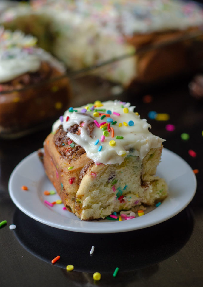 Rollos de canela Funfetti: rollos de levadura simples rellenos con canela dulce y pegajosa y salpicados con chispas. ¡Difunde con un glaseado de queso crema fácil para un desayuno o un placer indulgente!