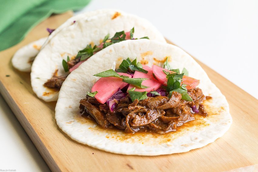 Taco Tuesday no tiene que ser difícil cuando preparas estos Tacos de Mole de Cerdo Lento de Olla de Cocción Lenta para la cena de esta semana. Cubra con rábanos en escabeche para un crujiente picante.